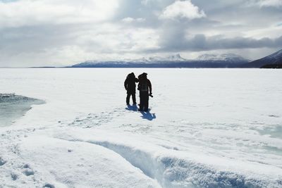 People on sea shore against sky during winter