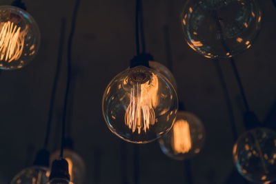 Close-up of illuminated light bulbs hanging from ceiling