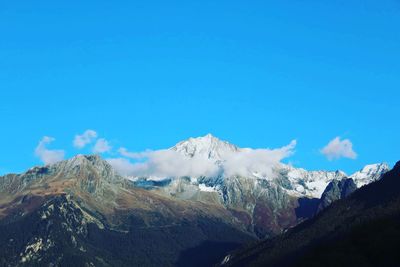 Scenic view of snowcapped mountains against blue sky