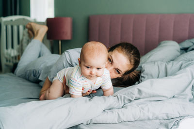 Mom is in bed with her little daughter. the kid learns to crawl on the bed. maternal care