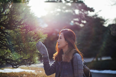 Woman touching tree during winter