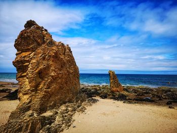 Rock formation on beach against sky