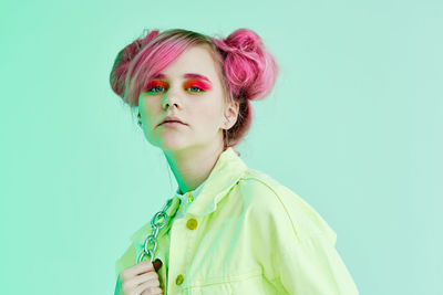 Portrait of young woman standing against blue background