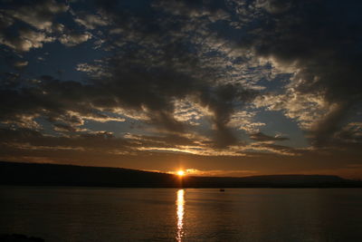 Scenic view of lake against dramatic sky during sunset