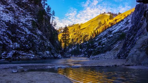 Scenic view of river by mountains against sky