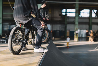 Young males staying with their bikes on the ramp. bmx riders is performing tricks in skatepark.