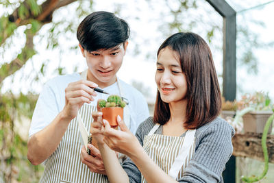 Smiling friends analyzing succulent plant