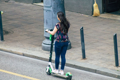 Rear view of woman standing on sidewalk