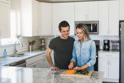 Happy friends standing by kitchen at home