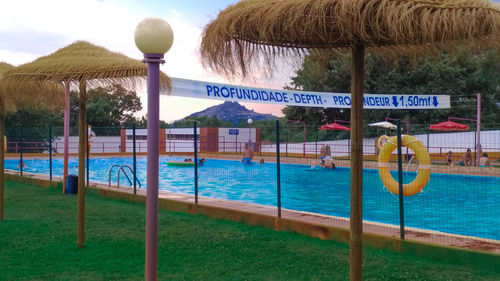 Swimming pool hanging by railing against sky