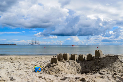 Sandcastles at beach against cloudy sky