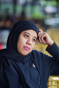 Portrait of indonesian muslim woman wearing black hijab with bokeh.