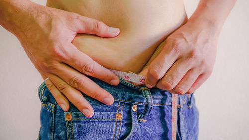 Midsection of woman measuring her waist