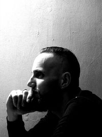 Portrait of young man looking away against wall