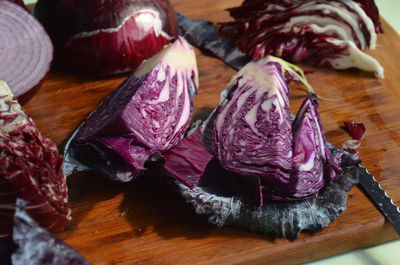 Cut red cabbage on cutting board, knife, red onion, radiccio