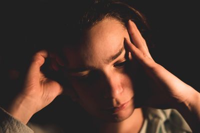 Close-up of sad man against black background