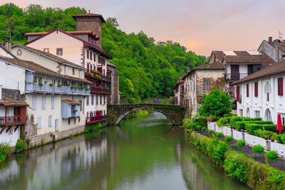 Arch bridge over river amidst buildings against sky