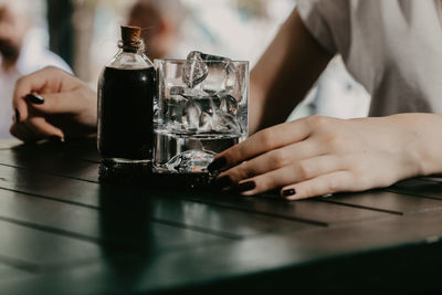 Midsection of woman holding drink on table