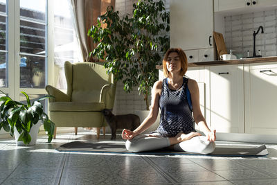 Middle aged woman practicing meditation at home, calm senior middle aged lady in toga pose