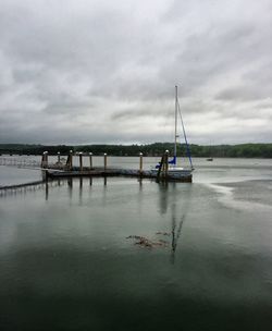 Boats in sea against cloudy sky