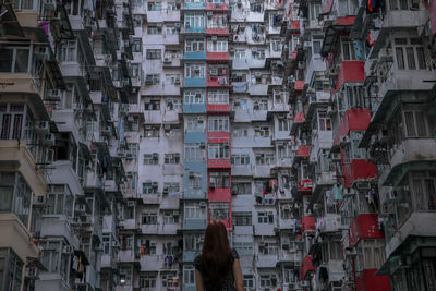 Rear view of woman standing against buildings in city