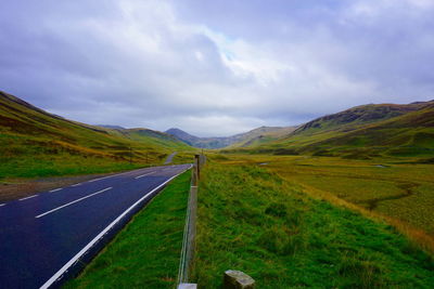 Road amidst green landscape against sky