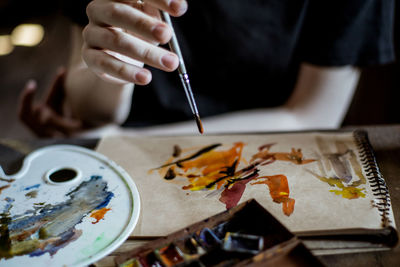 Midsection of man painting in book