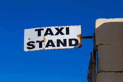 Low angle view of road sign against clear blue sky