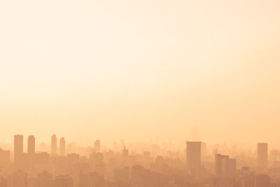 Modern buildings in city against sky during sunset