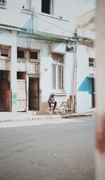 Man riding bicycle on road against building