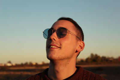 Portrait of young man wearing sunglasses against sky during sunset