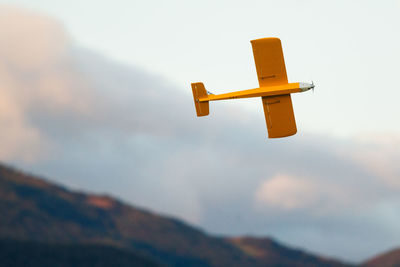 Low angle view of toy airplane flying against sky