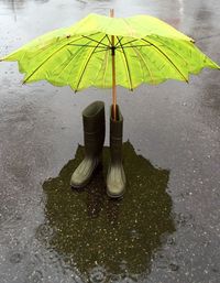 Umbrella in rubber boot on street during rain