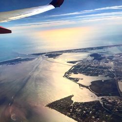 Aerial view of airplane wing over landscape against sky