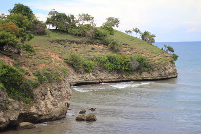 Scenic view of rocks by sea against sky