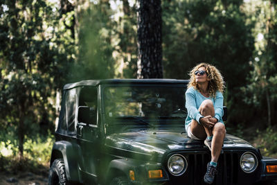 Woman wearing sunglasses while sitting on car