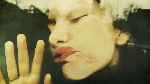 Close-up portrait of young woman pushing face on window