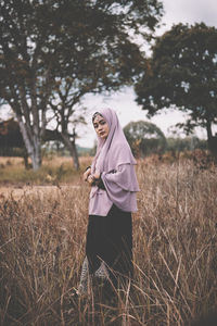 Portrait of young woman standing on grassy field