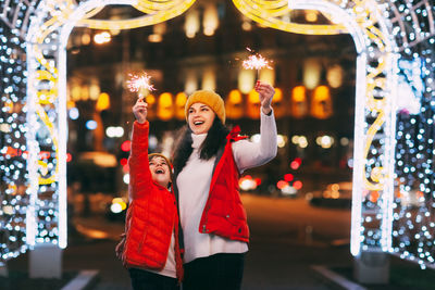 A beautiful boy and his mother celebrate new year or christmas with sparklers on the background