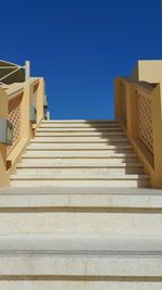 Low angle view of stairs against clear blue sky