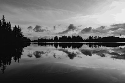 Scenic view of lake by silhouette trees against sky