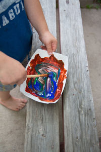 Low section of boy mixing colors in plate on wooden table