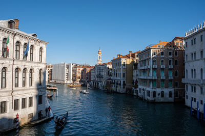 Canal amidst buildings in city against clear sky