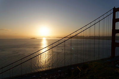 Bridge over sea against sky during sunset