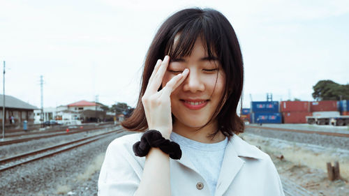 Portrait of beautiful woman holding camera against sky