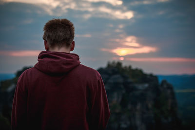 Rear view of man against cloudy sky during sunset