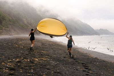 Rear view of women running with hammock on beach