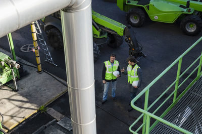 Engineers holding hardhats discussing at recycling plant