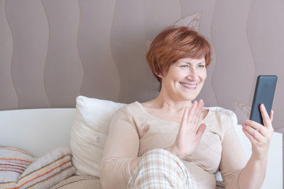 Portrait of smiling woman using mobile phone at home