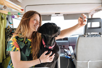 Woman taking selfie with dog in camper van